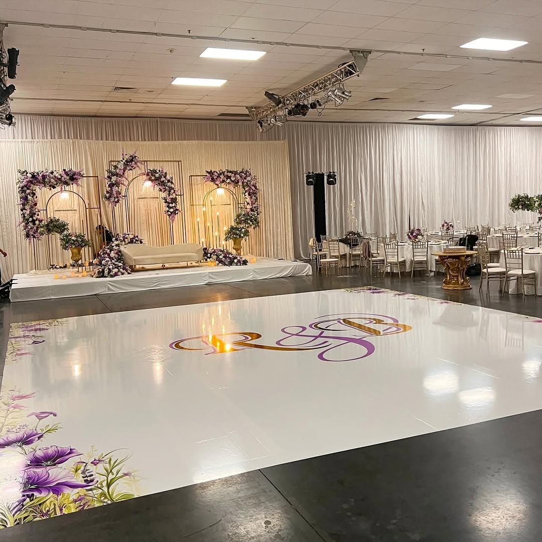 Glossy white dance floor rental with a printed centre monogram installed in a ballroom for a formal event