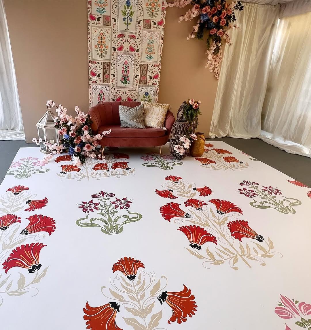 White dance floor rental printed with red and gold carnation artwork in front of a lounge setup
