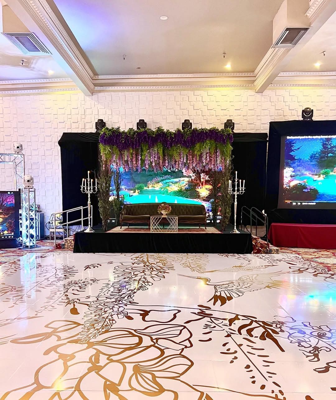 Blush dance floor rental with gold botanical line art in front of a lit reception stage