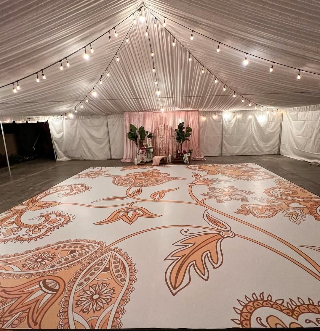 Peach paisley dance floor rental running the length of a string-lit tent
